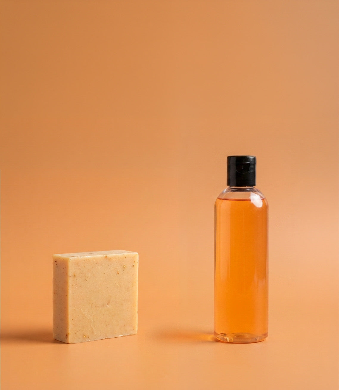 citrus natural soap bar standing next to a body wash bottle with orange background